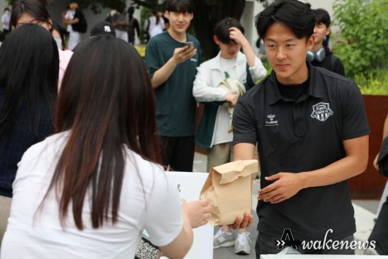 8일 아주대 학생회관 앞에서 열린 찾아가는 사랑의 밥차 ‘청년들 힘내세요’ 무료 급식 행사에 참여한 수원FC 이승우 선수가 한 대학생에게 햄버거와 음료수를 건네고 있다.